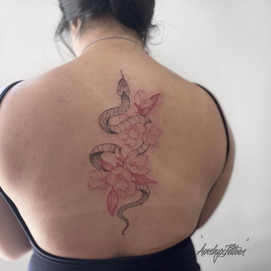 Fine-line snake and cherry blossom back tattoo with red accents by AinsleyXTattoos